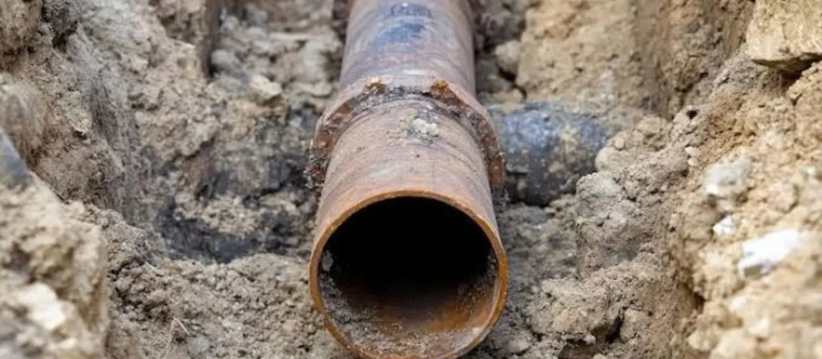 Exposed rusted sewer line in an excavated trench, sewer line repair in Clearfield, UT